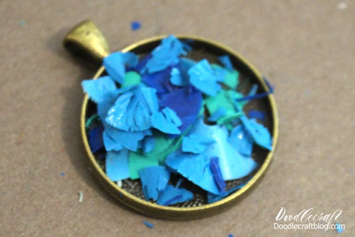 bronze vintage empty necklace pendant filled with blue and green crayon shavings epoxy jewelry step by step diy tutorial