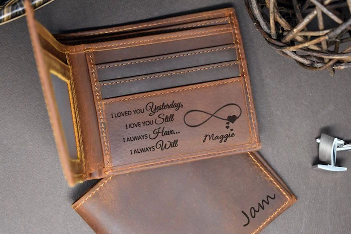 brown leather wallet with personalised message engraved inside valentines day gifts for boyfriend placed on gray surface