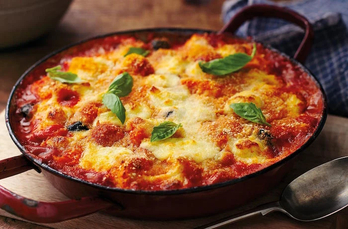casserole with baked gnocchi with tomato sauce grated cheese on top gnocchi recipe garnished with fresh basil leaves