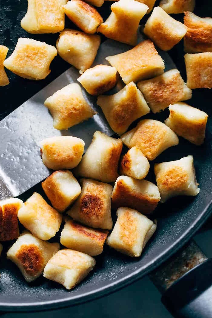cauliflower gnocchi being baked in black pan how to cook gnocchi stirred with metal spatula