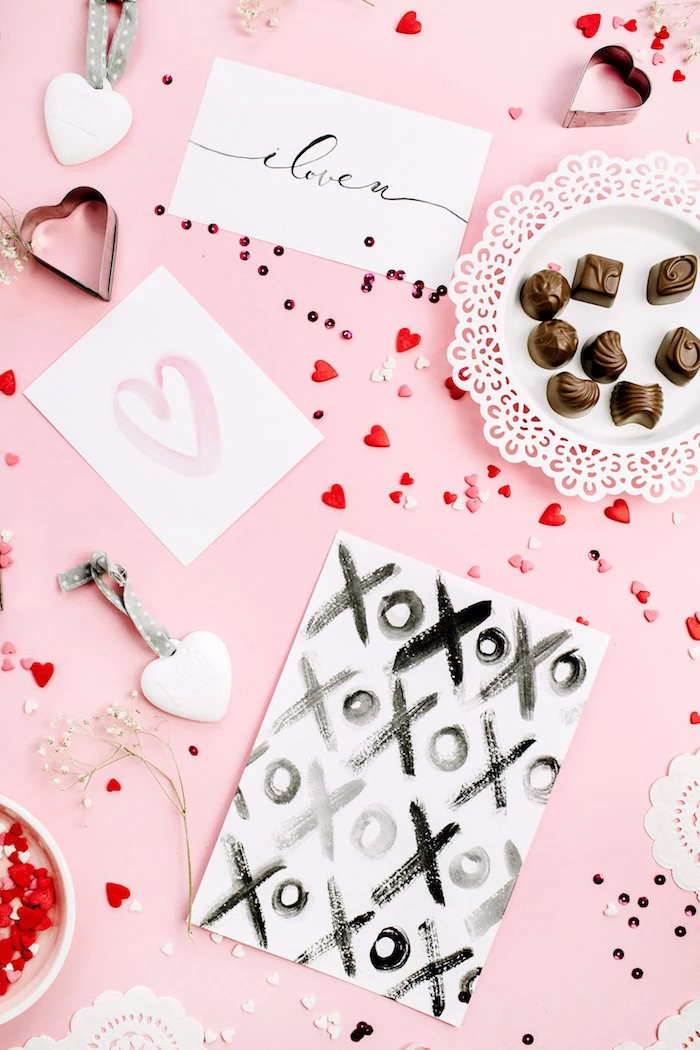 chocolates cards lots of small candy hearts scattered around pink surface valentine's day origin