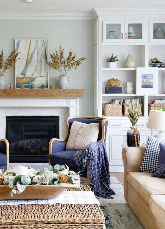 coastal decor blue armchairs beige sofa rattan table placed in front of fireplace white bookshelf on the side
