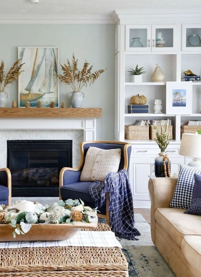 coastal decor blue armchairs beige sofa rattan table placed in front of fireplace white bookshelf on the side