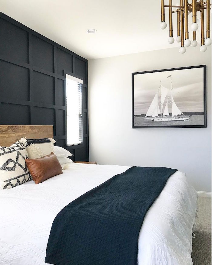 coastal living room bedroom with black accent wall bed with wooden bed frame framed painting of boat on the wall