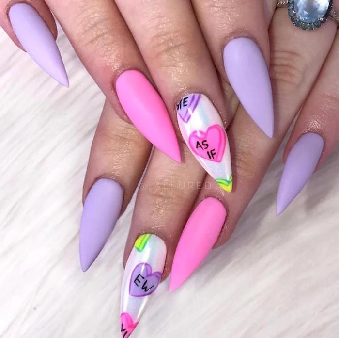 conversation hearts drawn on middle finger valentines day nail art pink and purple matte nail polish on long stiletto nails