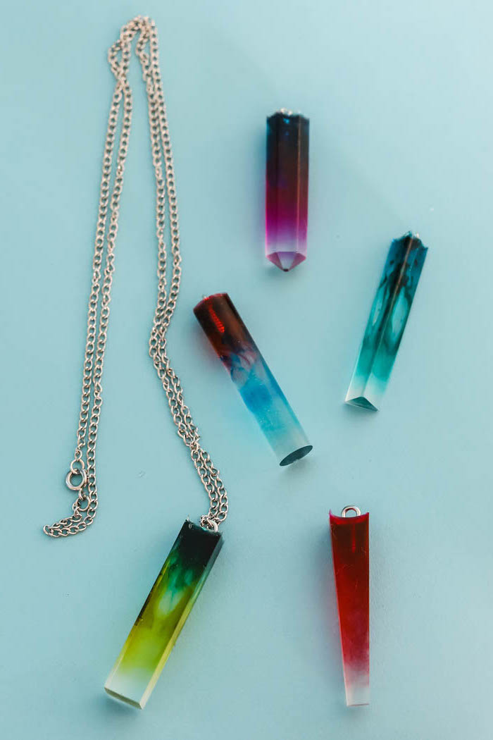 crystal like necklace pendants in different colors how to make resin jewelry blue pink red green placed on blue surface