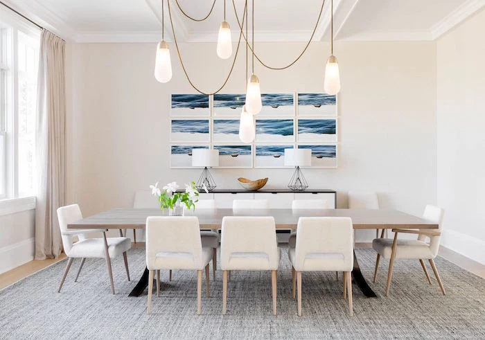 dining room with long wooden table white chairs around it small beach house framed art on white wall