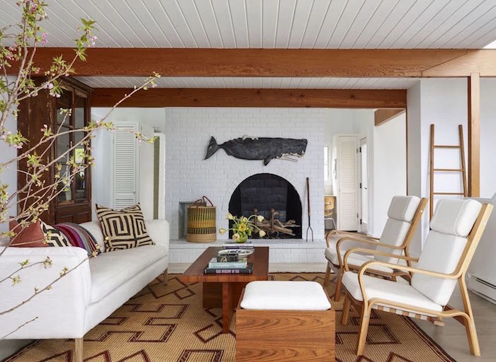 fireplace on white brick wall beach decor ceiling with exposed wod beams white sofa and armchairs wooden coffee table