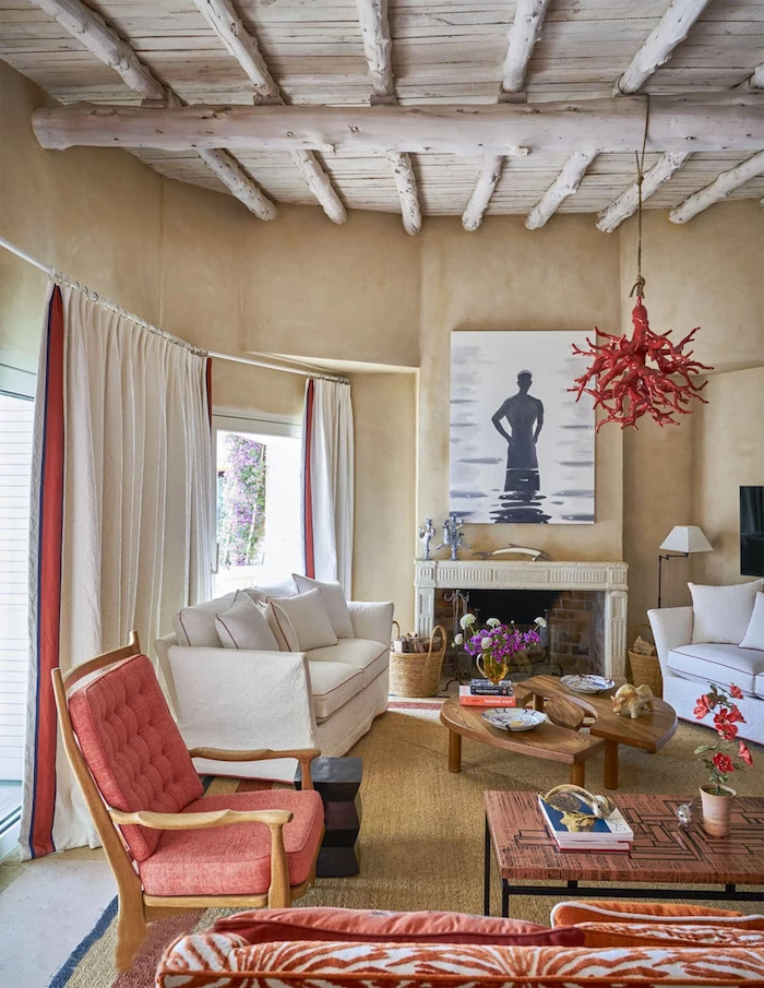 framed art above the fireplace nautical decor two white sofas red armchair exposed wood beams on the ceiling