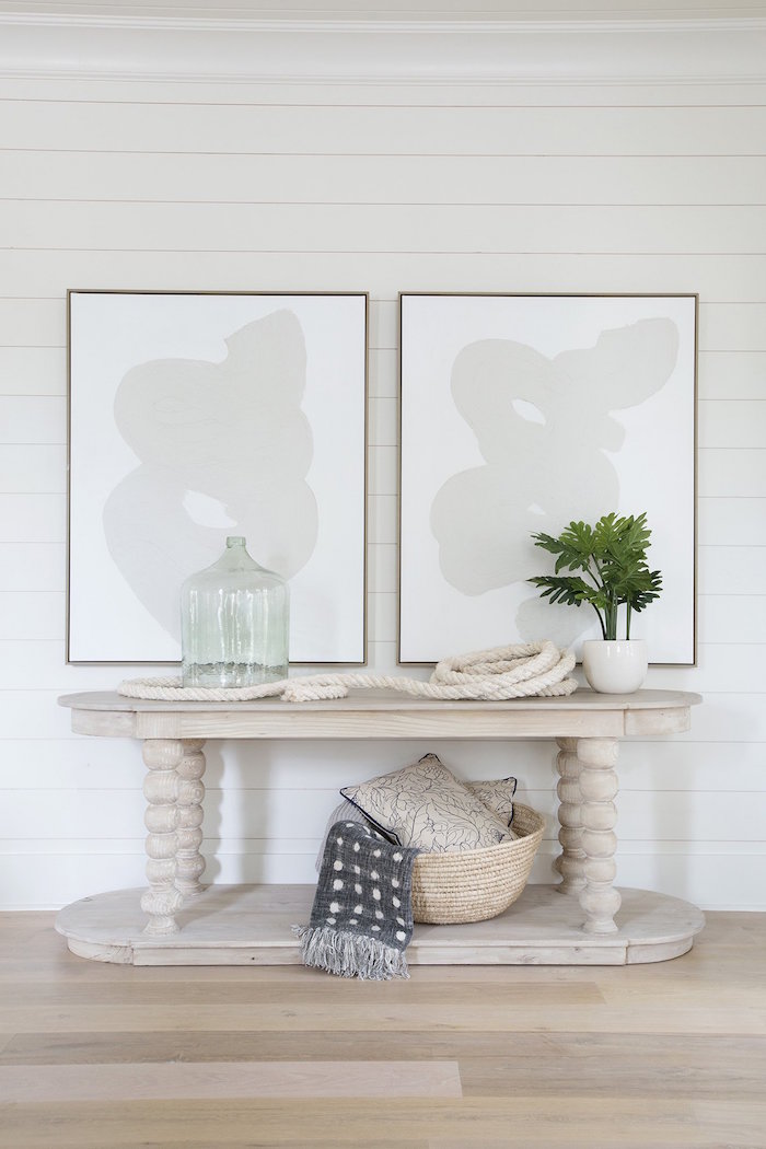 framed art on white shiplap wall above wooden table with decorations made from rope nautical decor hallway design