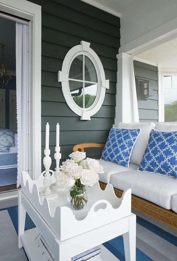 front porch with white sofa with blue throw pillows white wooden coffee table black shiplap walls beach decor