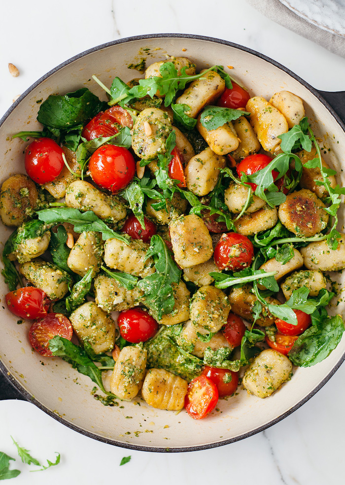 gnocchi with basil pesto fresh cherry tomatoes arugula spinach inside white pan gnocchi recipe