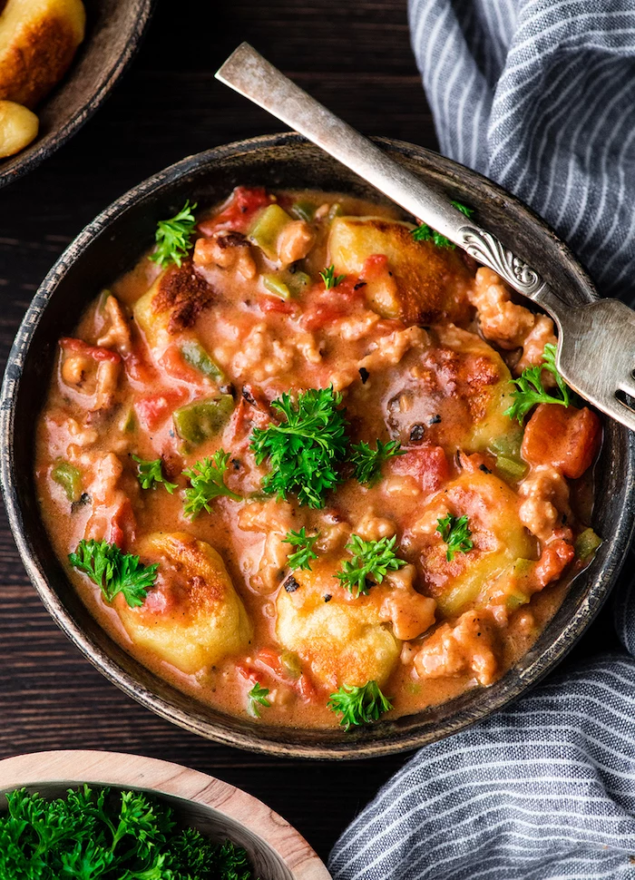 gnocchi with cheesy sauce tomatoes and sausage how to make gnocchi inside wooden bowl with fork on the side