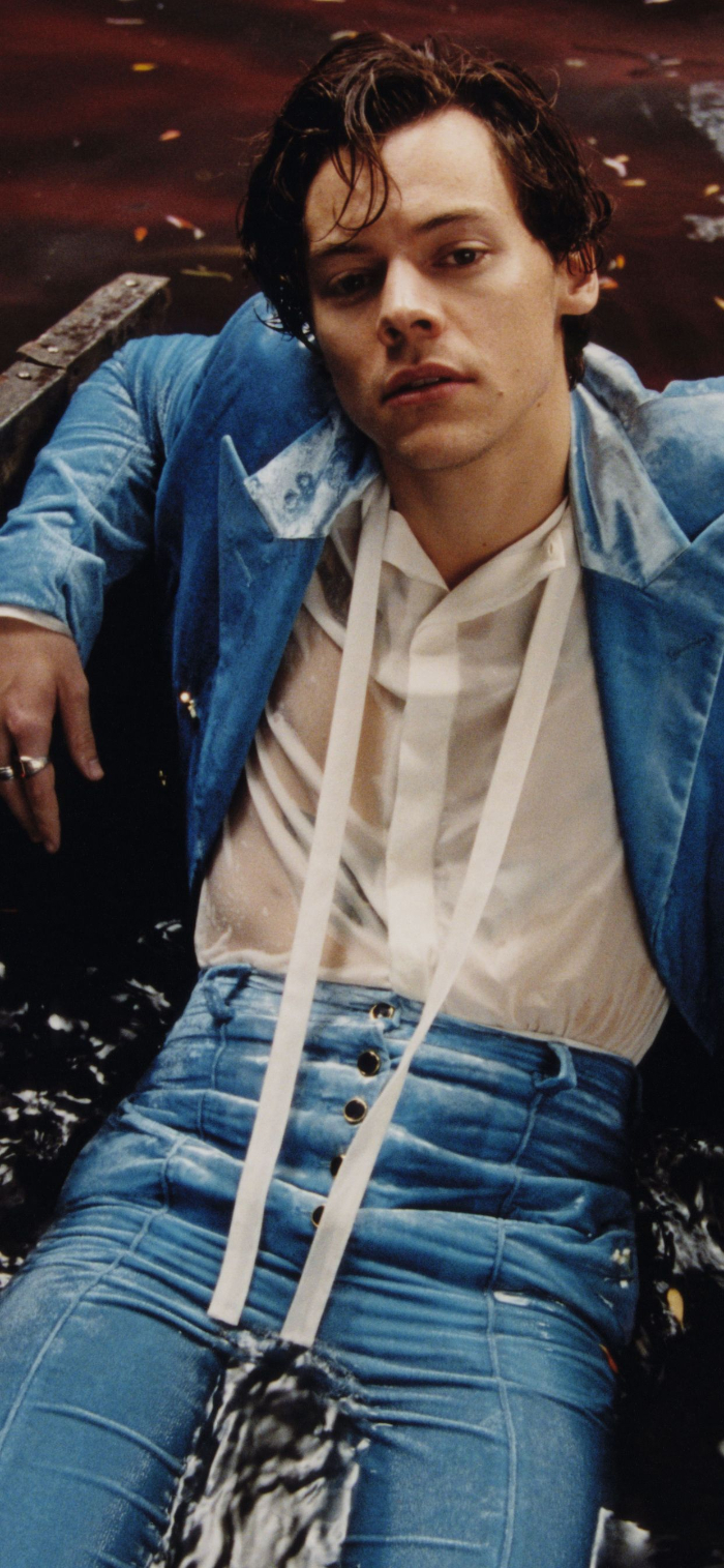 harry styles background sitting in water wearing blue suit white shirt lots of rings on his hand