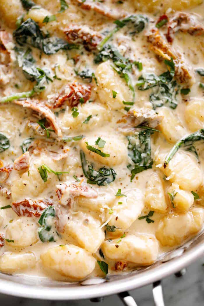 healthy gnocchi recipes creamy tuscan gnocchi with cheesy sauce sun dried tomatoes basil cooking in metal pan
