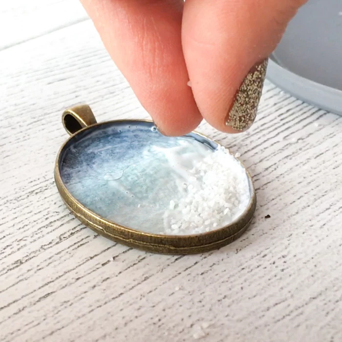 jewelry making for beginners vintage bronze necklace pendant being filled with salt placed on white wooden surface
