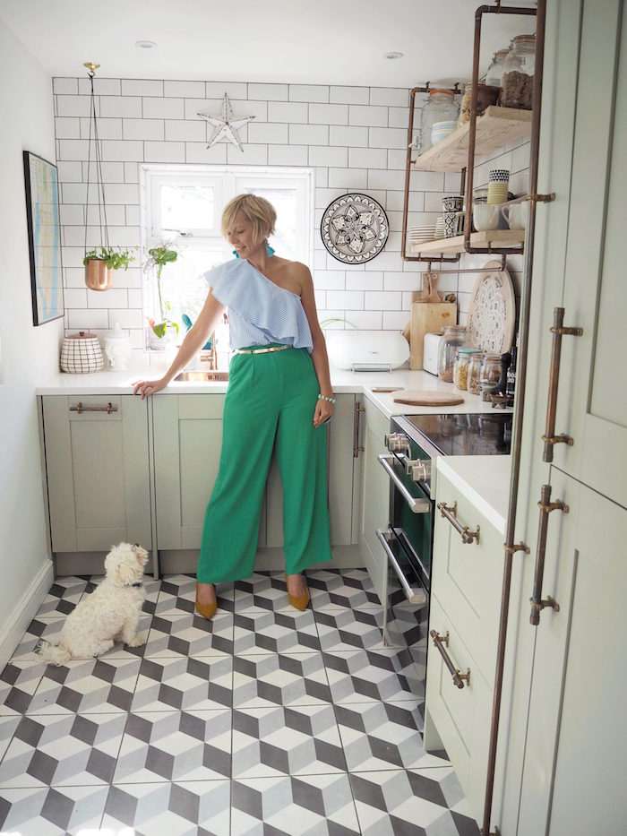 kitchen decorating ideas woman standing in kitchen with open shelving white subway tiles backsplash gray and white tiled floor