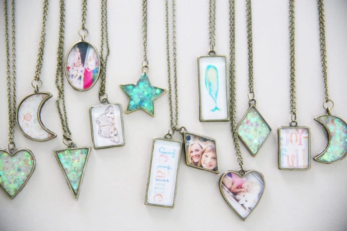 lots of different bronze necklaces in different shapes epoxy resin jewelry with photos and drawings inside placed on white surface
