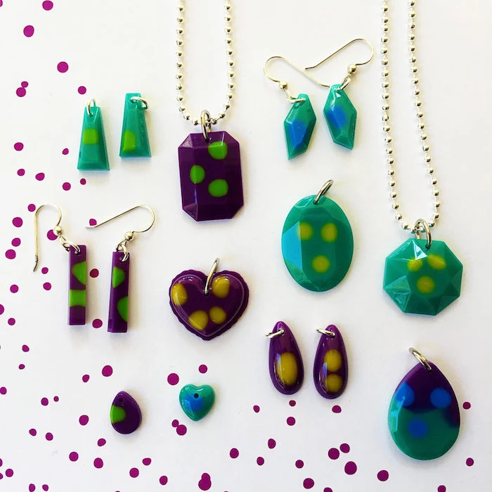 lots of different pendants and earrings in turquoise and purple with green yellow dots resin jewelry molds placed on white surface