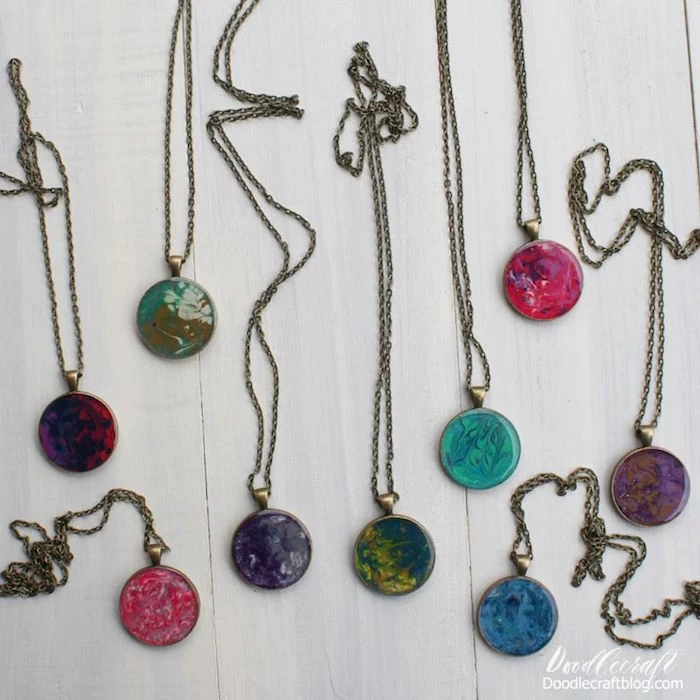 nine different marble necklace pendants making resin jewelry with vintage bronze chains arranged on white wooden surface