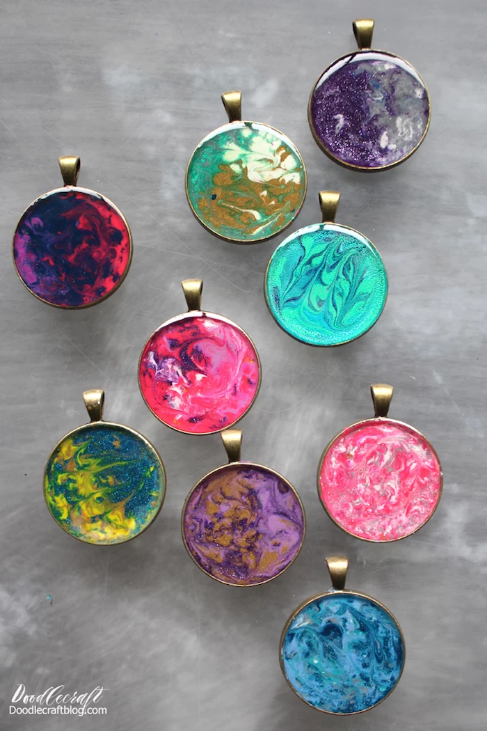 nine necklace pendants placed on marble surface all in different colors epoxy jewelry green blue red pink purple yellow