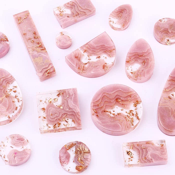 pink and gold marble resin jewelry in different shapes rose gold arranged on white surface