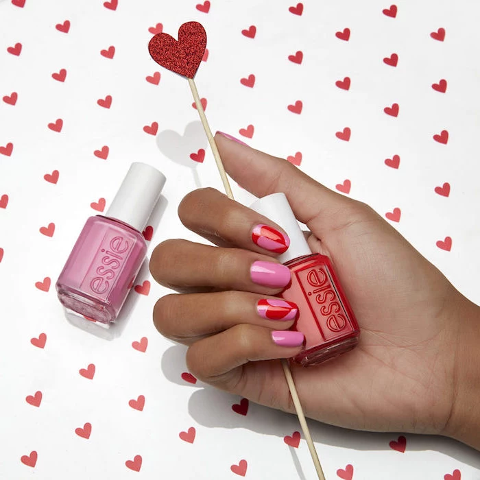 pink and red nail polish with hearts drawn on index and ring finger valentines nails short squoval nails
