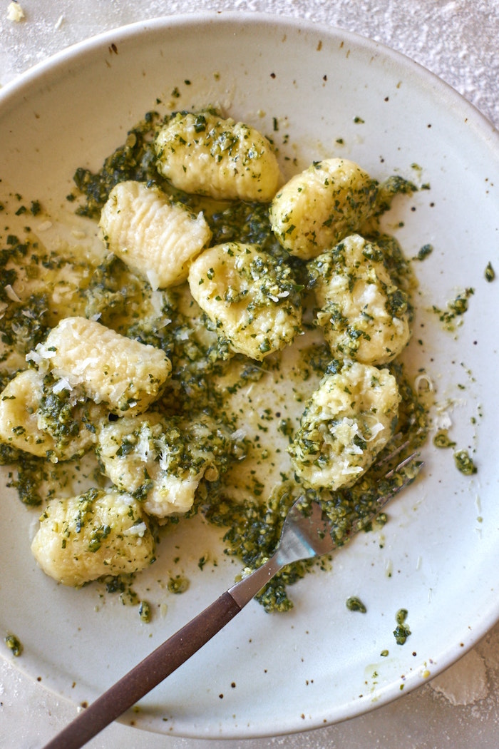 potato gnocchi with basil pesto sauce and parmesan cheese how to make gnocchi in white plate with fork on the side