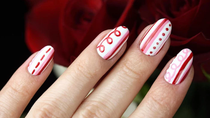 red and pink lines and dots drawn on white nail polish valentines day nails medium length almond nails