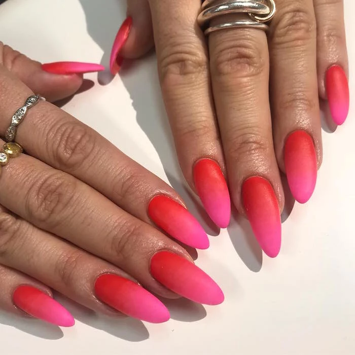 red and pink matte ombre nail polish valentine's day acrylic nails long almond nails on woman wearing silver rings