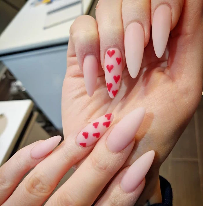 red hearts drawn on ring fingers cute nail designs beige matte nail polish on long stiletto nails