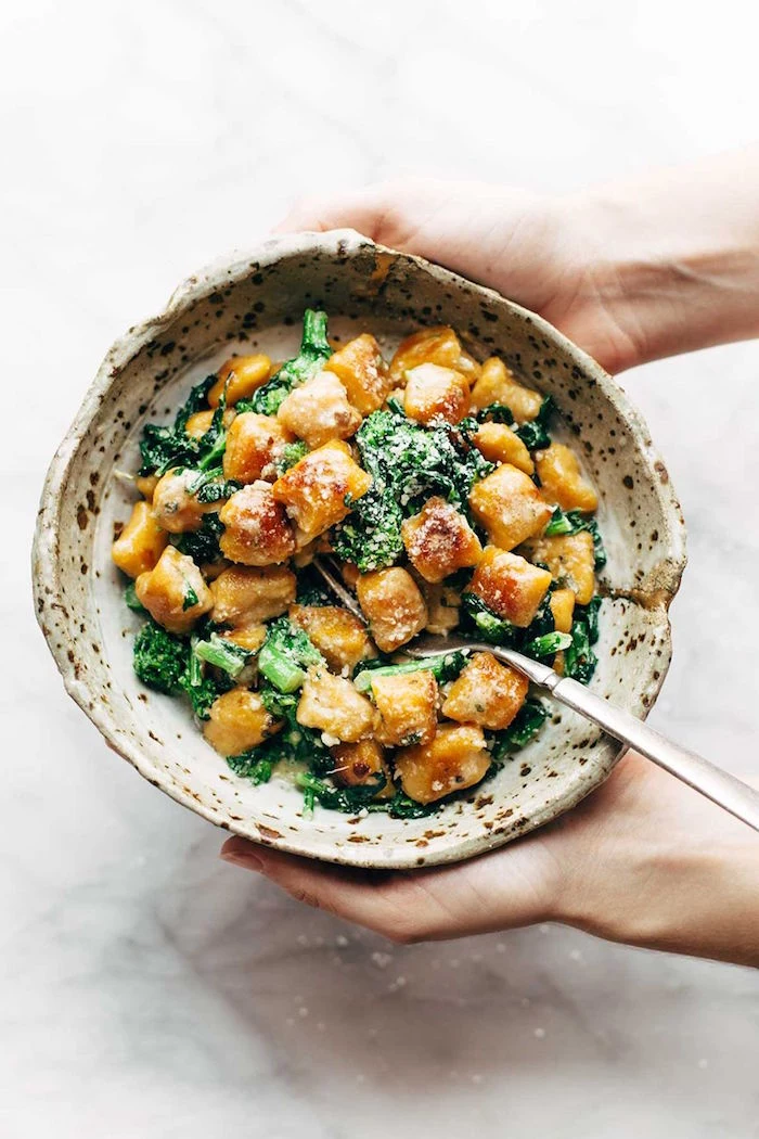 small bowl filled with baked sweet potato gnocchi with kale recipes using gnocchi garnished with parmesan cheese