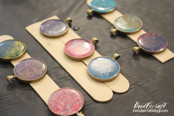 step by step diy tutorial making resin jewelry nine necklace pendants made in different marble colors placed on wooden sticks