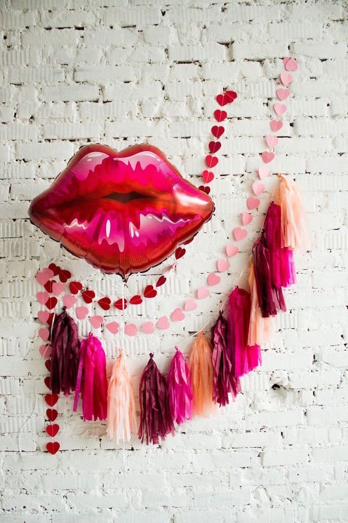 tassel garland in gold pink and red lips shaped balloon valentine's day origin pink red hearts garlands hanging on white brick wall