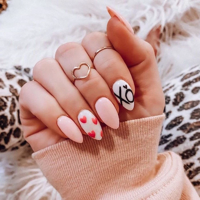 valentine's day acrylic nails white nail polish xo written on index finger red hearts on middle finger