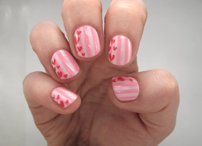 valentines day nail ideas stripes in different shades of pink on short squoval nails red hearts drawn on each nail