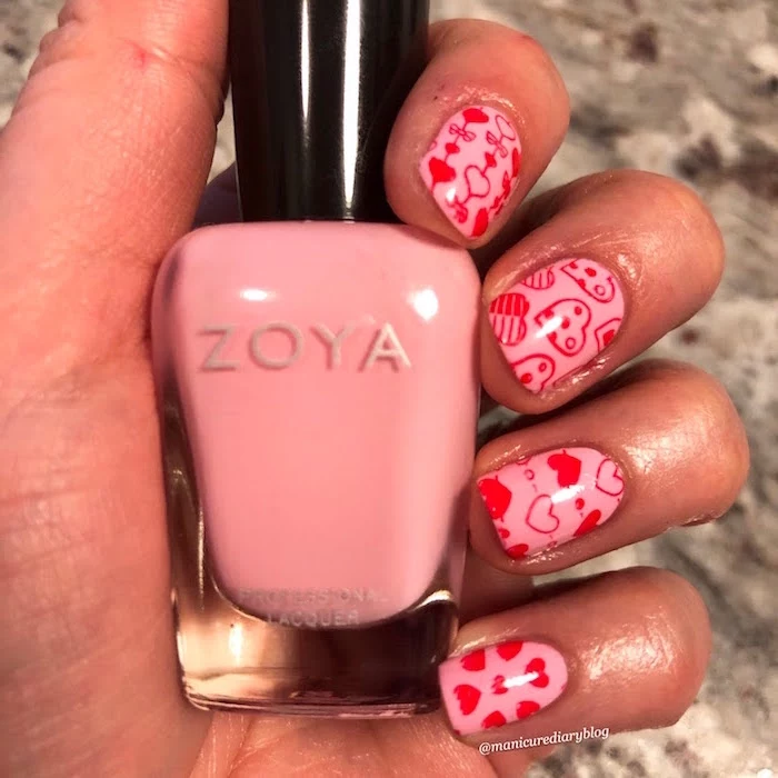 valentines day nails short squoval nails with pink nail polish red hearts in different shapes drawn on them