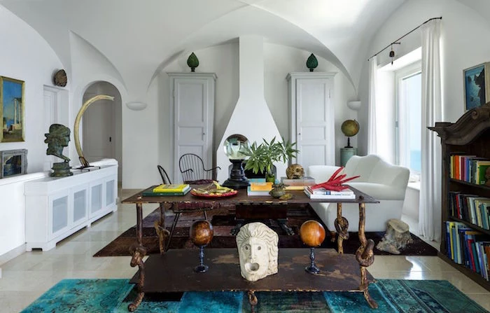 white walls and cathedral ceiling beach themed decor white sofa in front of fireplace vintage wooden table and bookshelf