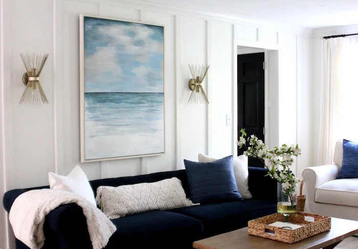 white walls ocean painting above blue velvet sofa beach bathroom decor wooden coffee table white armchair