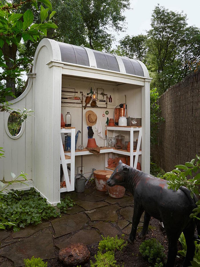 white wooden shed diy storage space with wooden shelves and countertops hangers on the walls