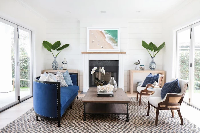 wooden coffee table blue velvet sofa white armchairs in front of fireplace coastal decorating ideas black and white carpet