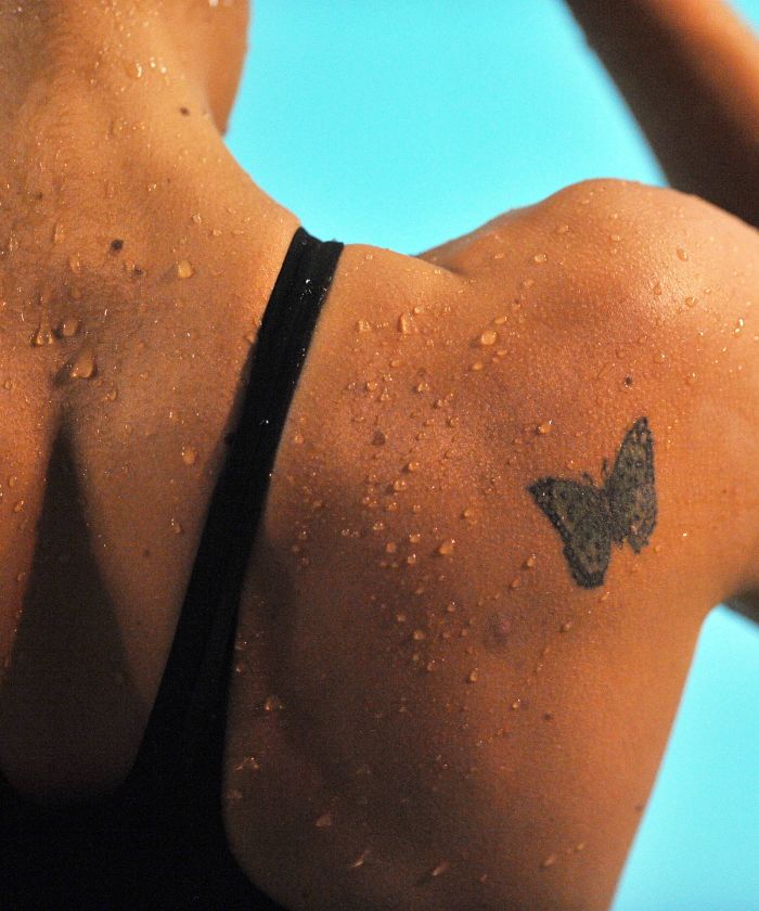 back of shoulder tattoo on woman wearing black swimsuit butterfly tattoo meaning black butterfly