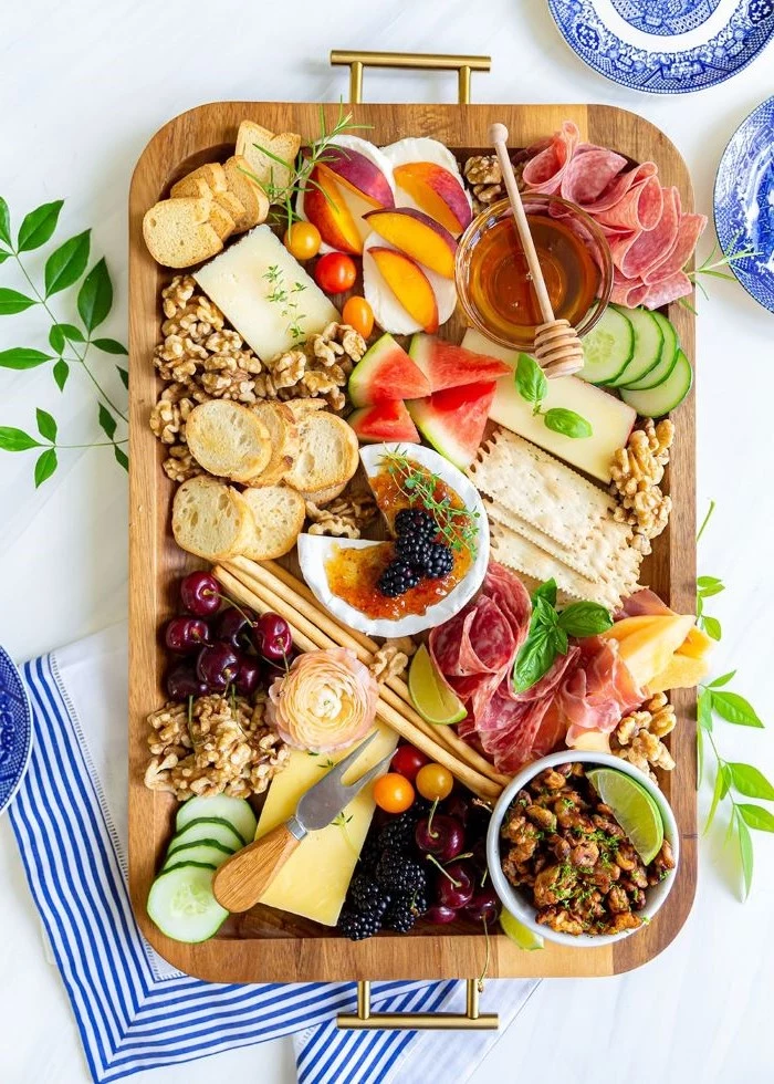 baked brie in the middle charcuterie board cheese meats fruits bread nuts on wooden tray