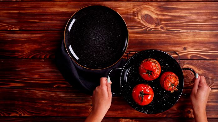 baked stuffed tomatoes in black baking dish finger food appetizers black plate placed on wooden surface