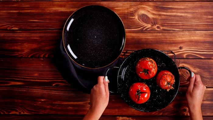 baked stuffed tomatoes in black baking dish finger food appetizers black plate placed on wooden surface