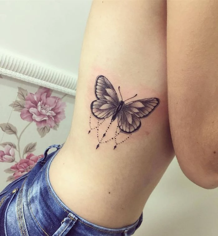 black and white butterfly tattoo on the side of the rib cage simple butterfly tattoo on woman wearing jeans