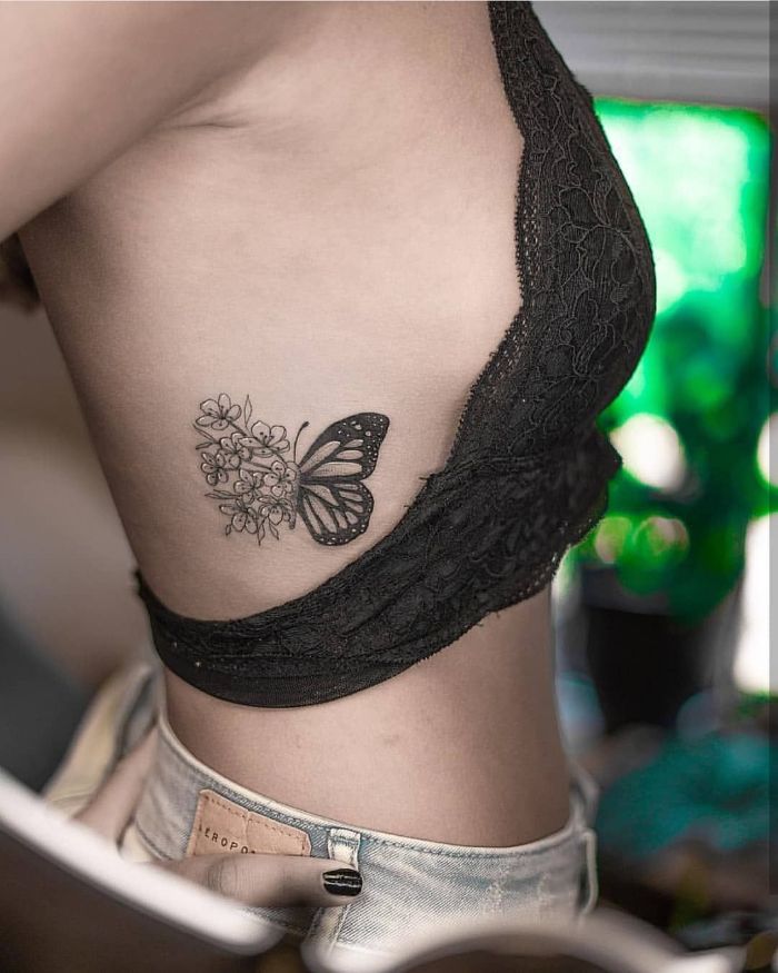 black lace top and jeans worn by woman with rib cage tattoo small butterfly tattoo half butterfly half flowers