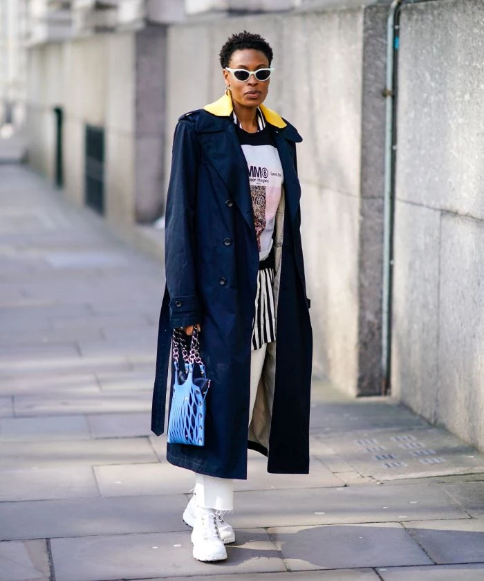 black long coat white pants white and black blouse mens streetwear worn by woman standing on the sidewalk