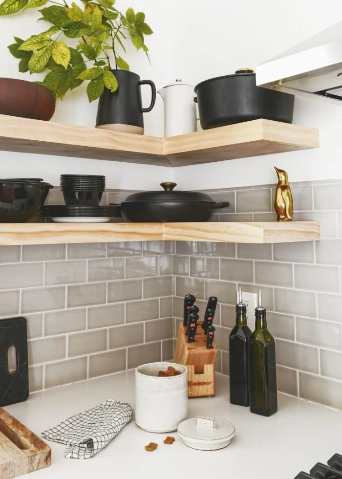 black pots and plates on wooden corner shelves floating kitchen shelves gray subway tiles backdrop white countertop