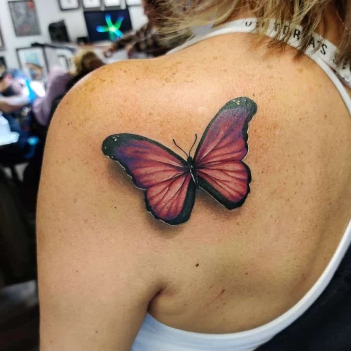 butterfly hand tattoo colored butterfly in orange and purple back of shoulder tattoo